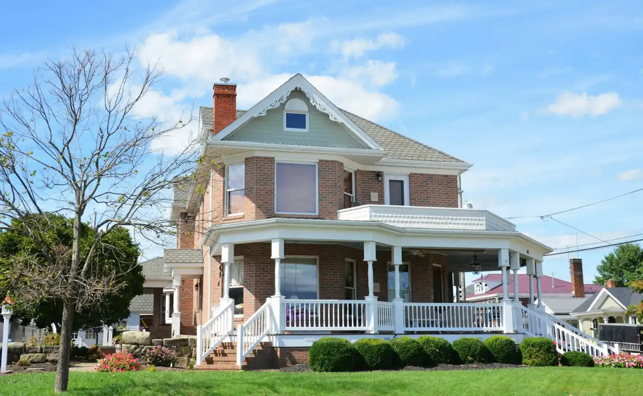 Two-story brick house with a white wraparound porch, brick steps, Greenville NC