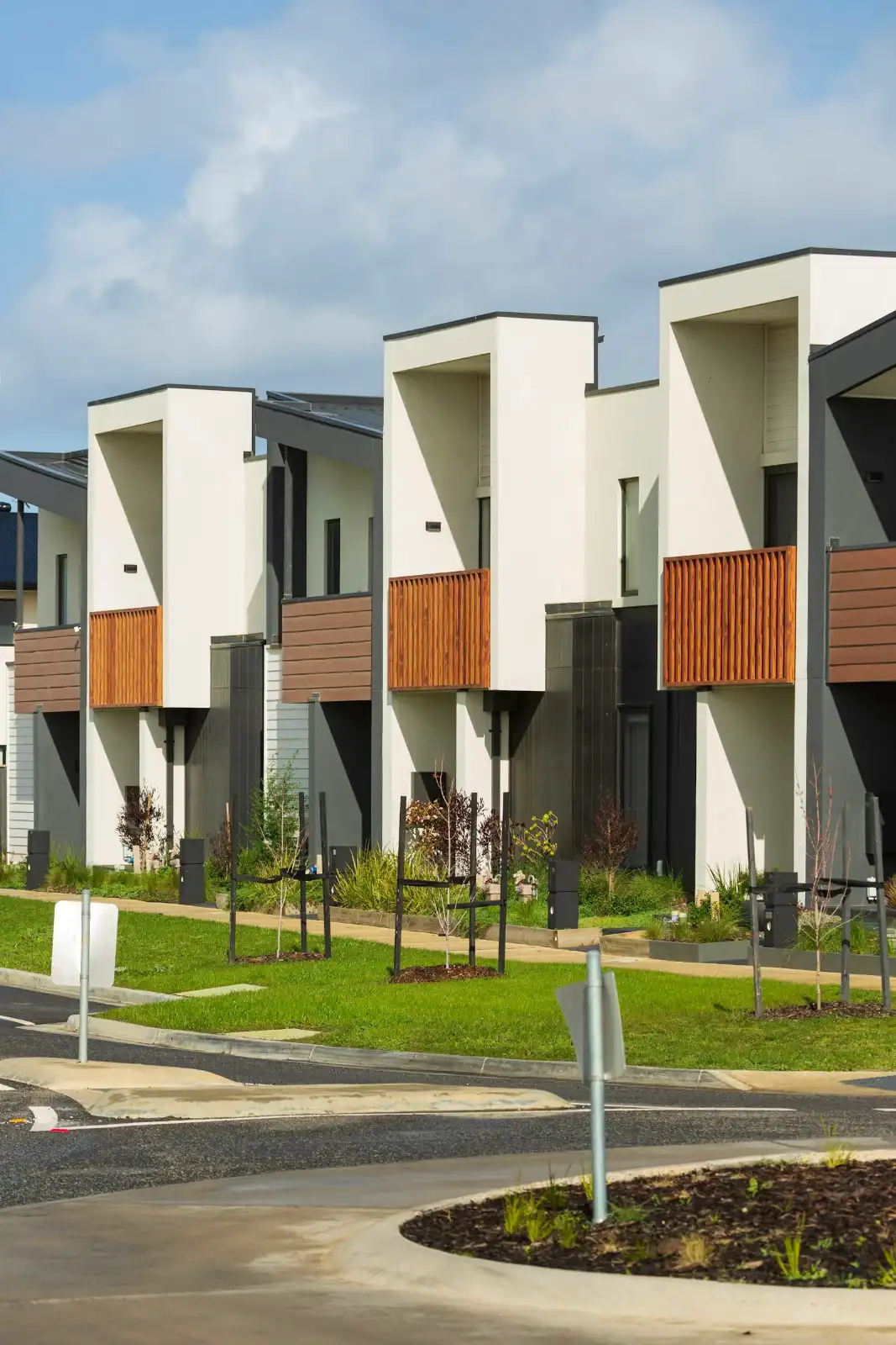 Modern townhouses with wooden balconies under a cloudy sky, concrete driveway in Greenville NC