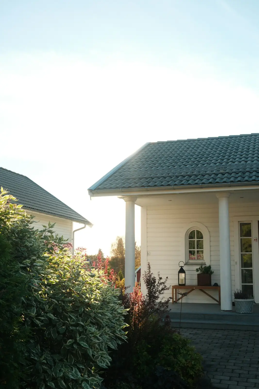 A white house with columns and a tiled roof in low golden light, concrete driveway in Greenville NC