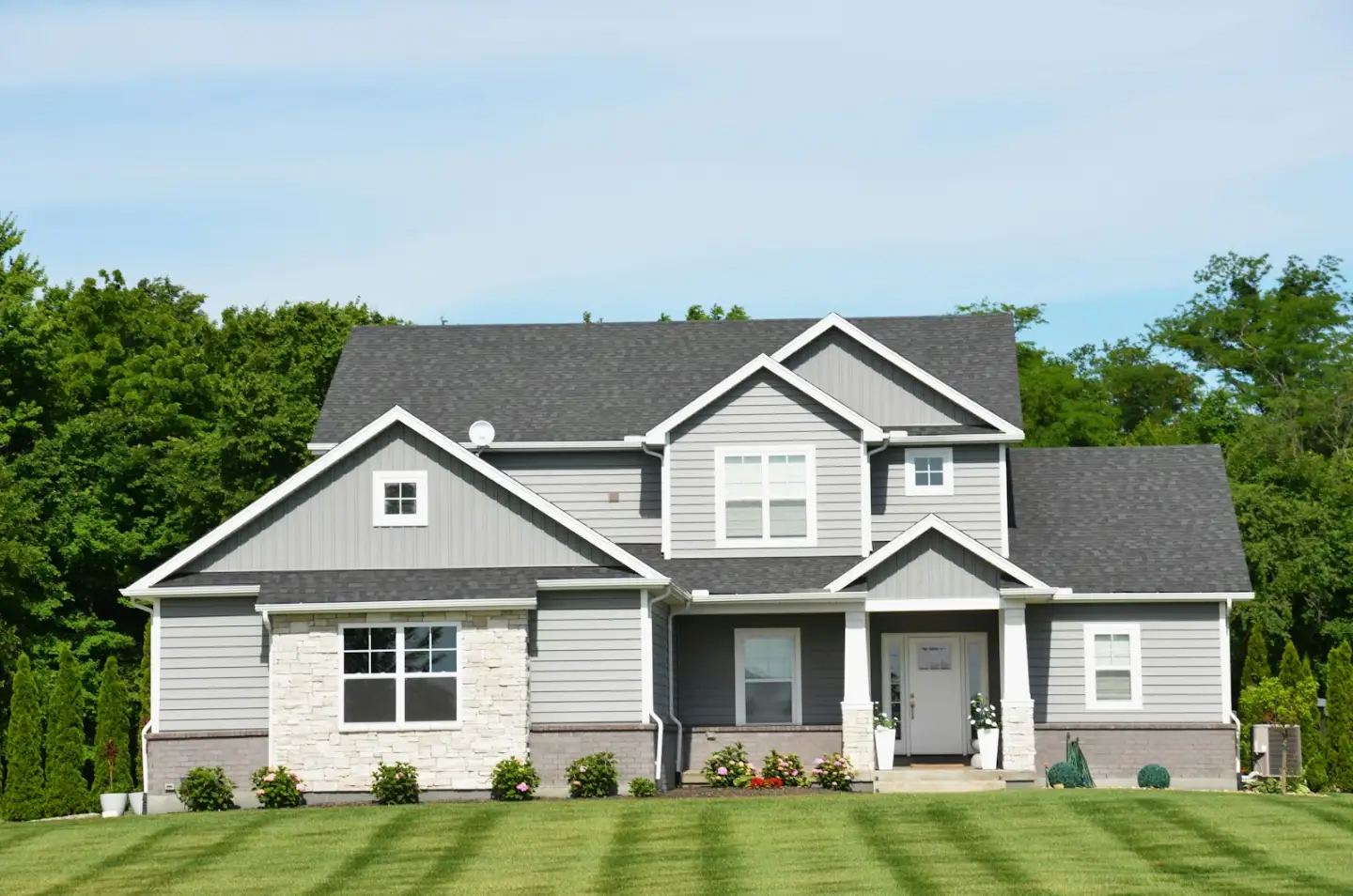 A modern grey house with a green lawn and trees, masonry and concrete in Washington NC