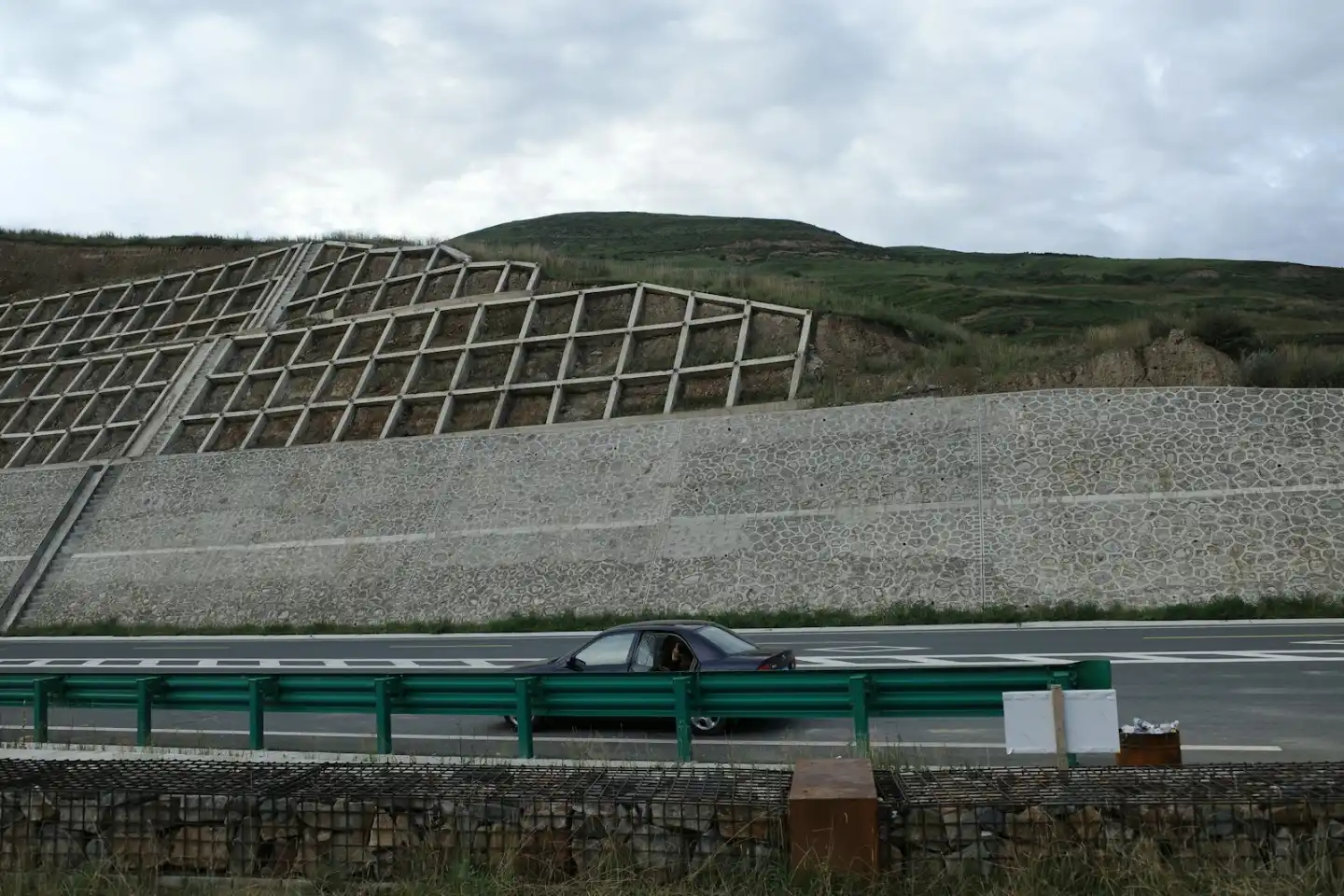 Car driving on highway next to retaining wall in Greenville NC