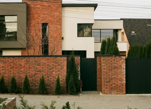 Brick fence with pillars in front of a modern home