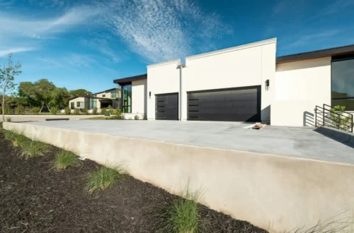 Modern house with two black garage doors under blue sky, concrete driveway in Greenville NC