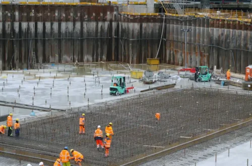 A group of construction workers standing around a construction site, concrete footing