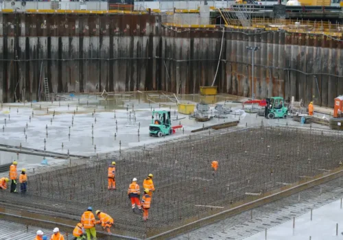 A group of construction workers standing around a construction site, concrete footing