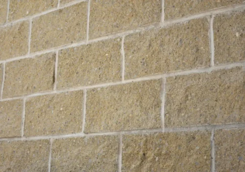 A tan brick wall with white grout, concrete footing in Greenville NC