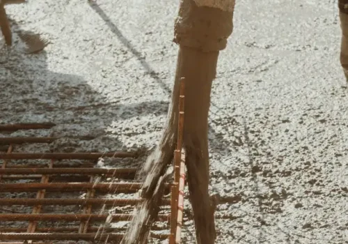 A worker pouring concrete onto a building under construction, concrete footing in Greenville NC