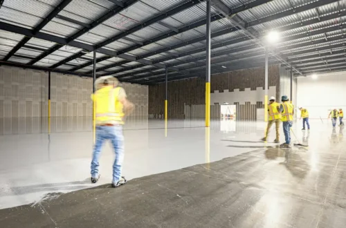 Workers in a large, empty warehouse with polished floors, concrete slab in Greenville NC