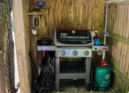 Gas grill with propane tank in wooden shelter, outdoor kitchen in Greenville NC