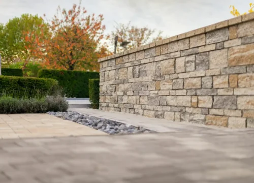 Stone wall with autumn trees and manicured hedges, retaining wall in Greenville NC