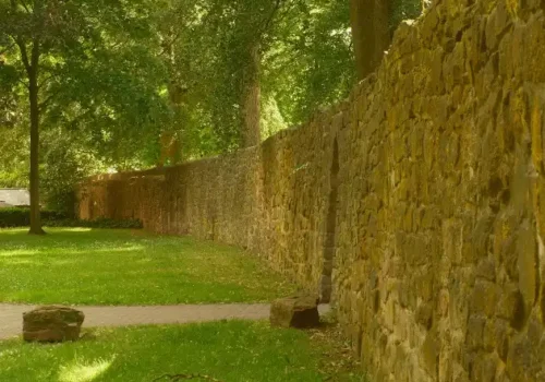 Long stone wall and green grass in a sunny park, stone masonry in Greenville NC