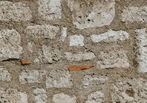 A rustic wall made of rough white stones and small red bricks, stone masonry in New Bern NC